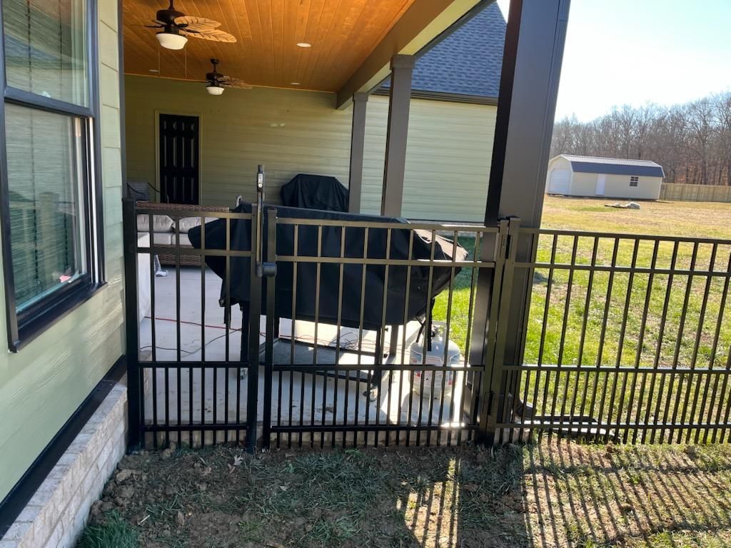 A metal fence surrounds a patio area in front of a house.