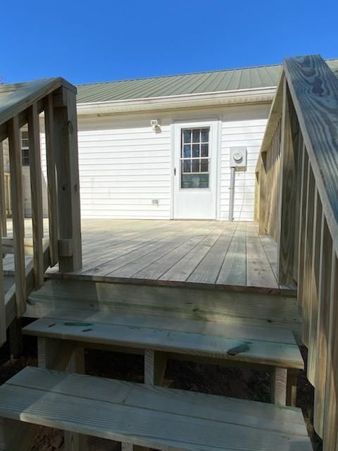 A wooden deck with stairs leading to a white house