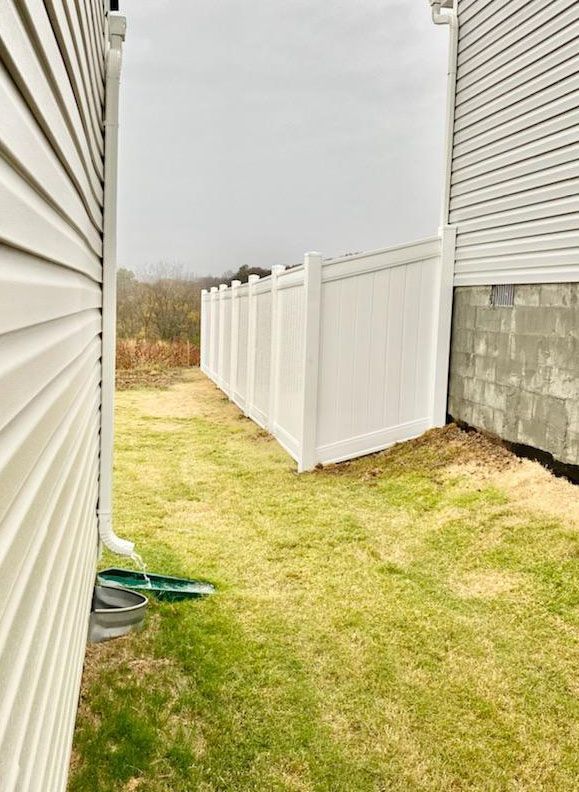 There is a white fence in the backyard of a house.