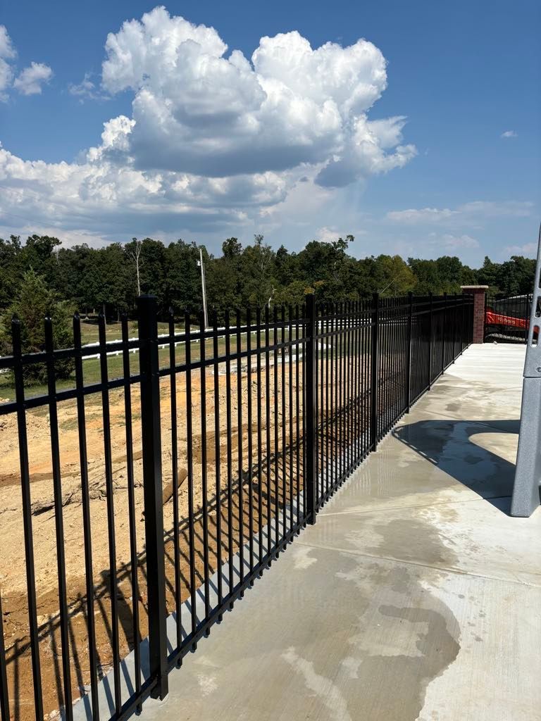 A black wrought iron fence surrounds a construction site
