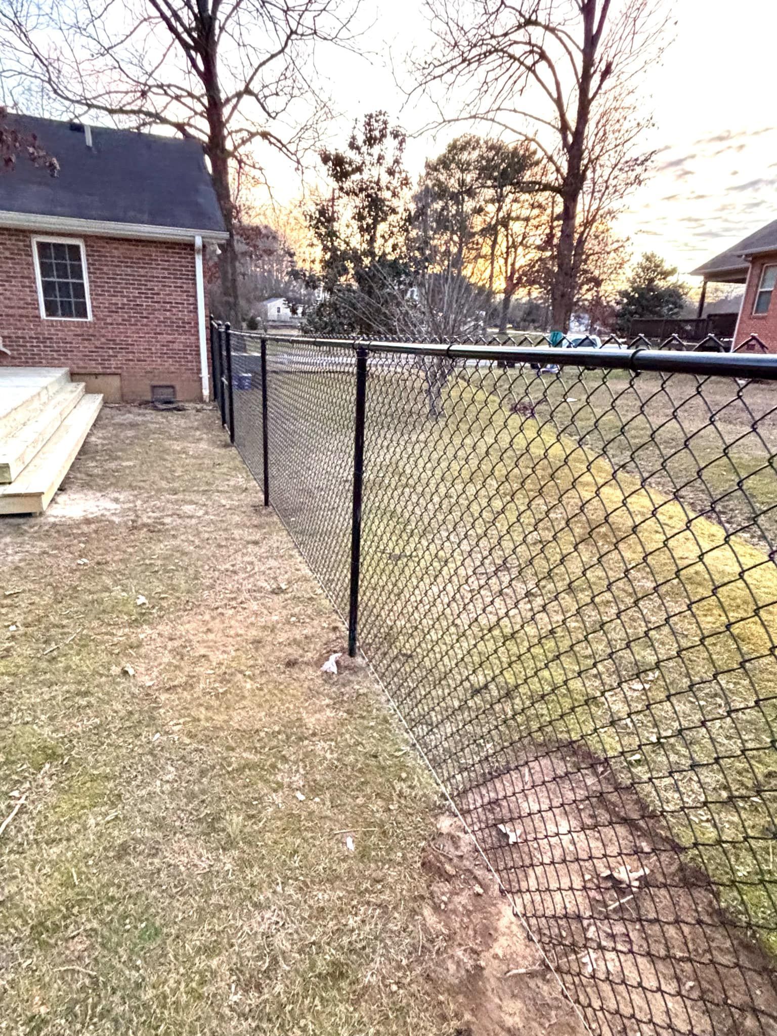 There is a chain link fence in the backyard of a house.