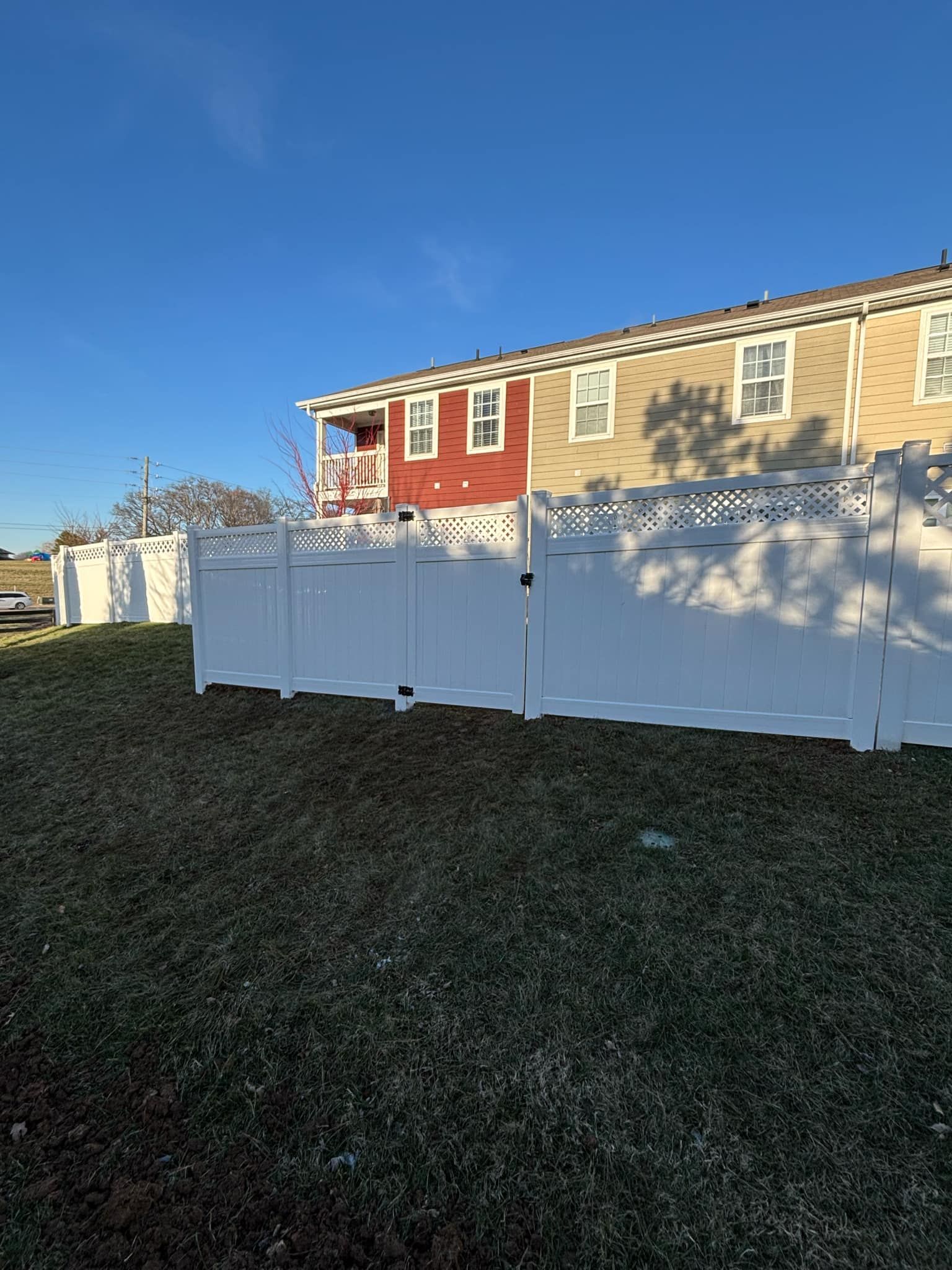 There is a white fence in front of a house.