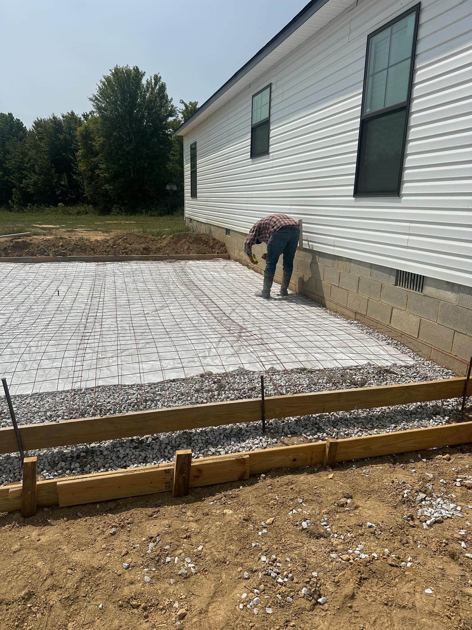A man is laying concrete in front of a house.