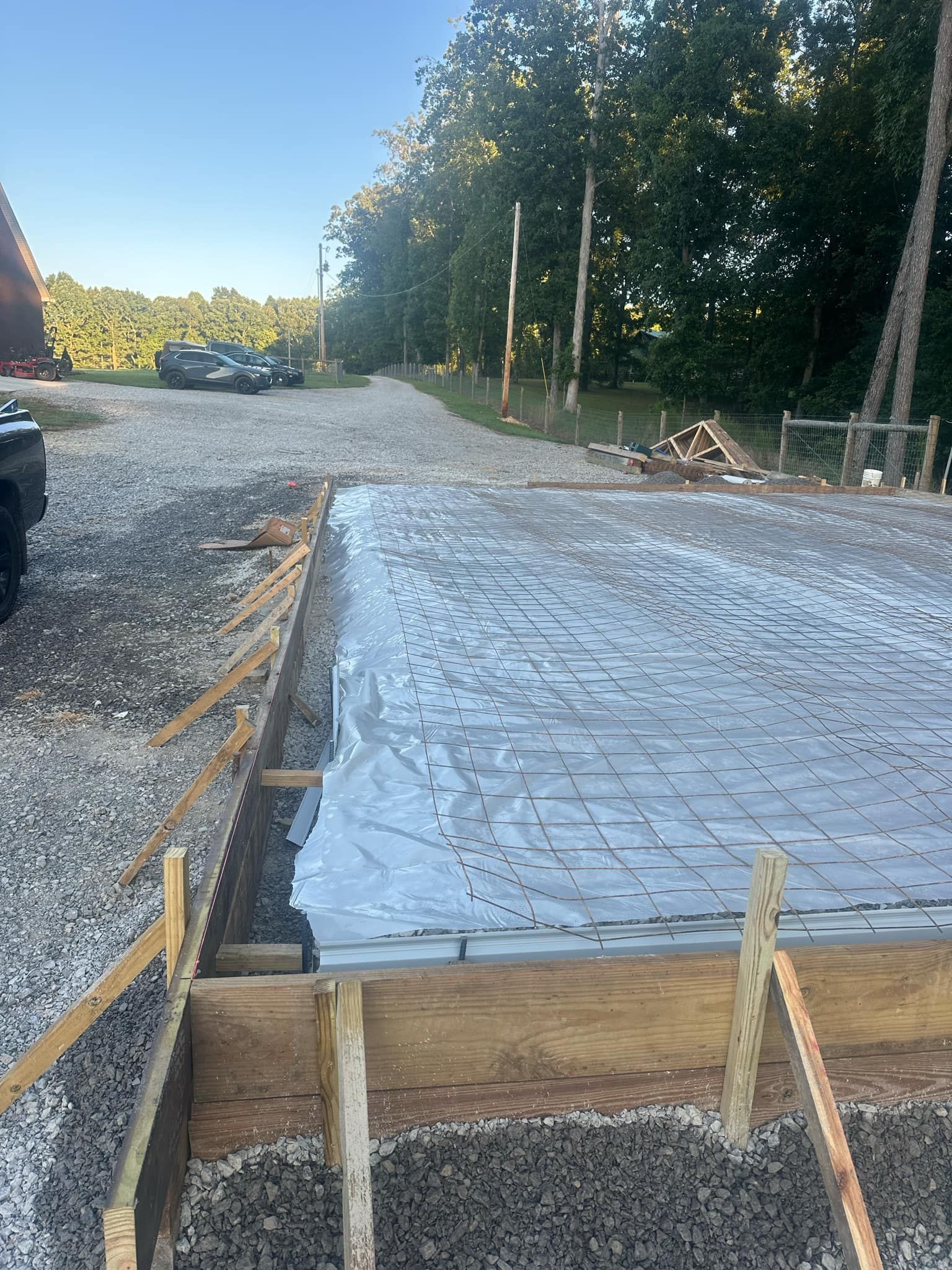 A truck is parked in a gravel lot next to a concrete slab.