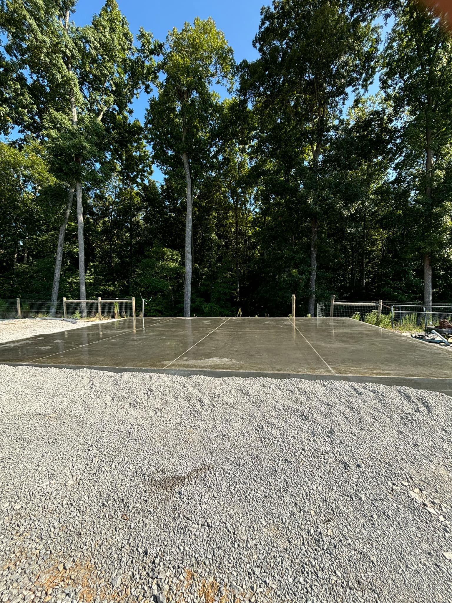 A gravel driveway surrounded by trees on a sunny day.