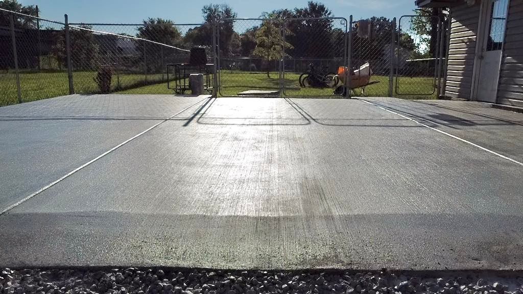 A concrete driveway with a fence in the background