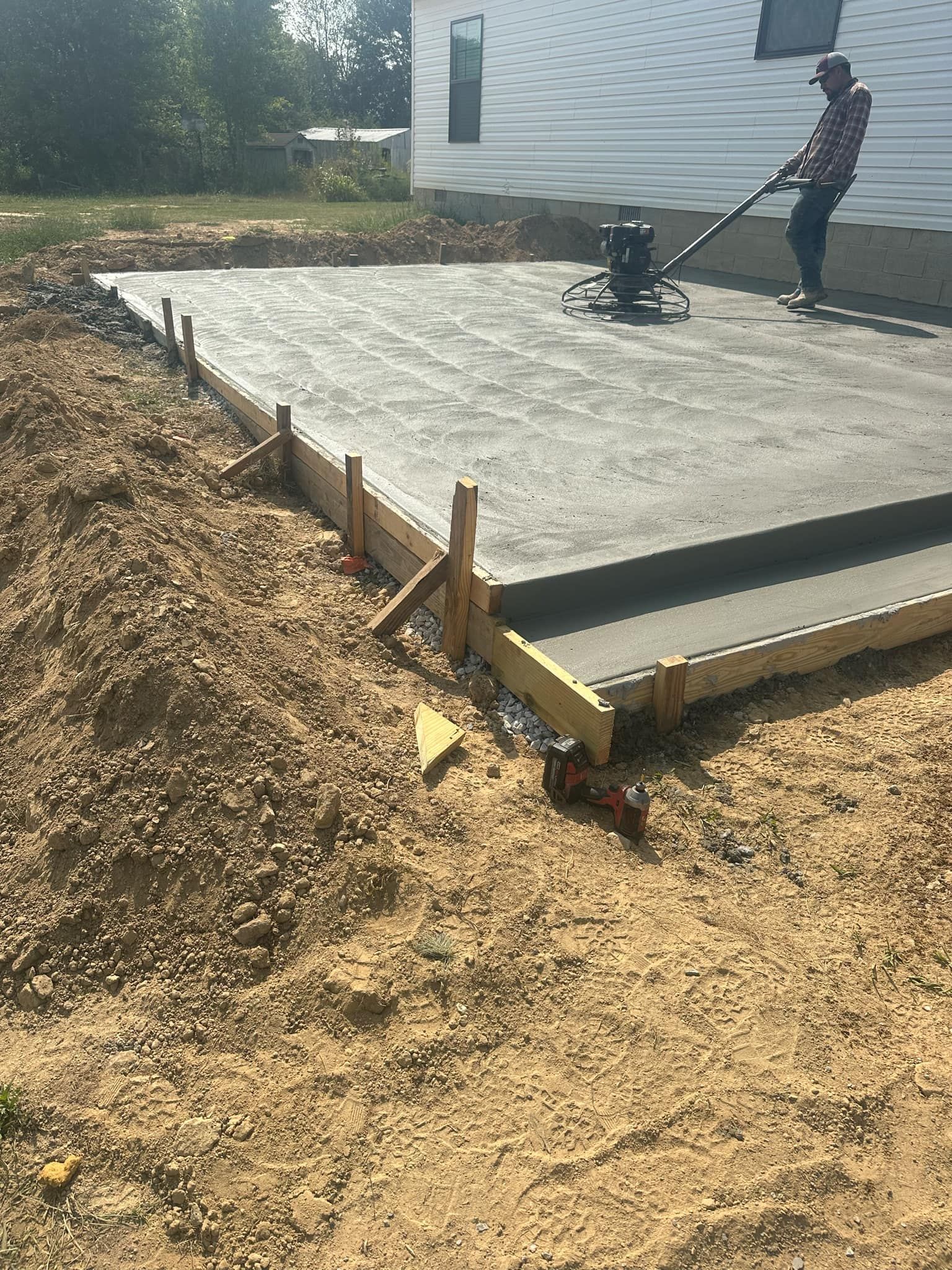 A man is using a machine to level a concrete slab.