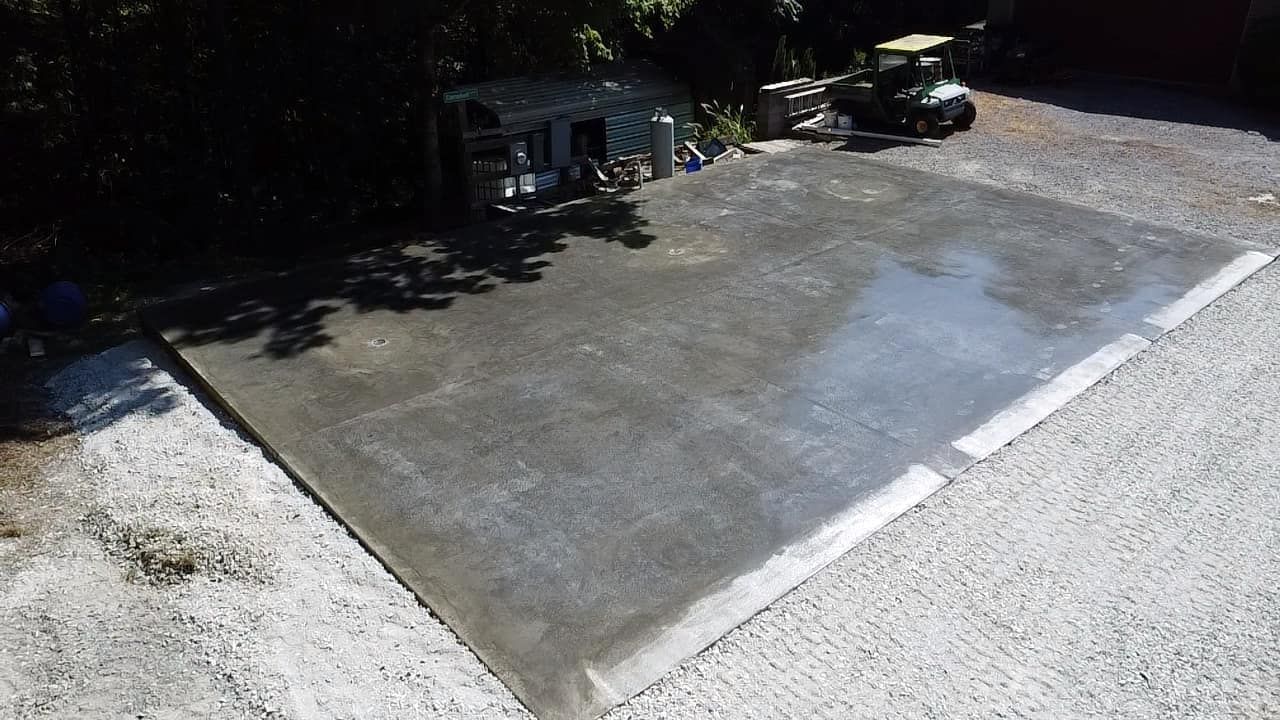 A concrete driveway with a golf cart parked in the background.