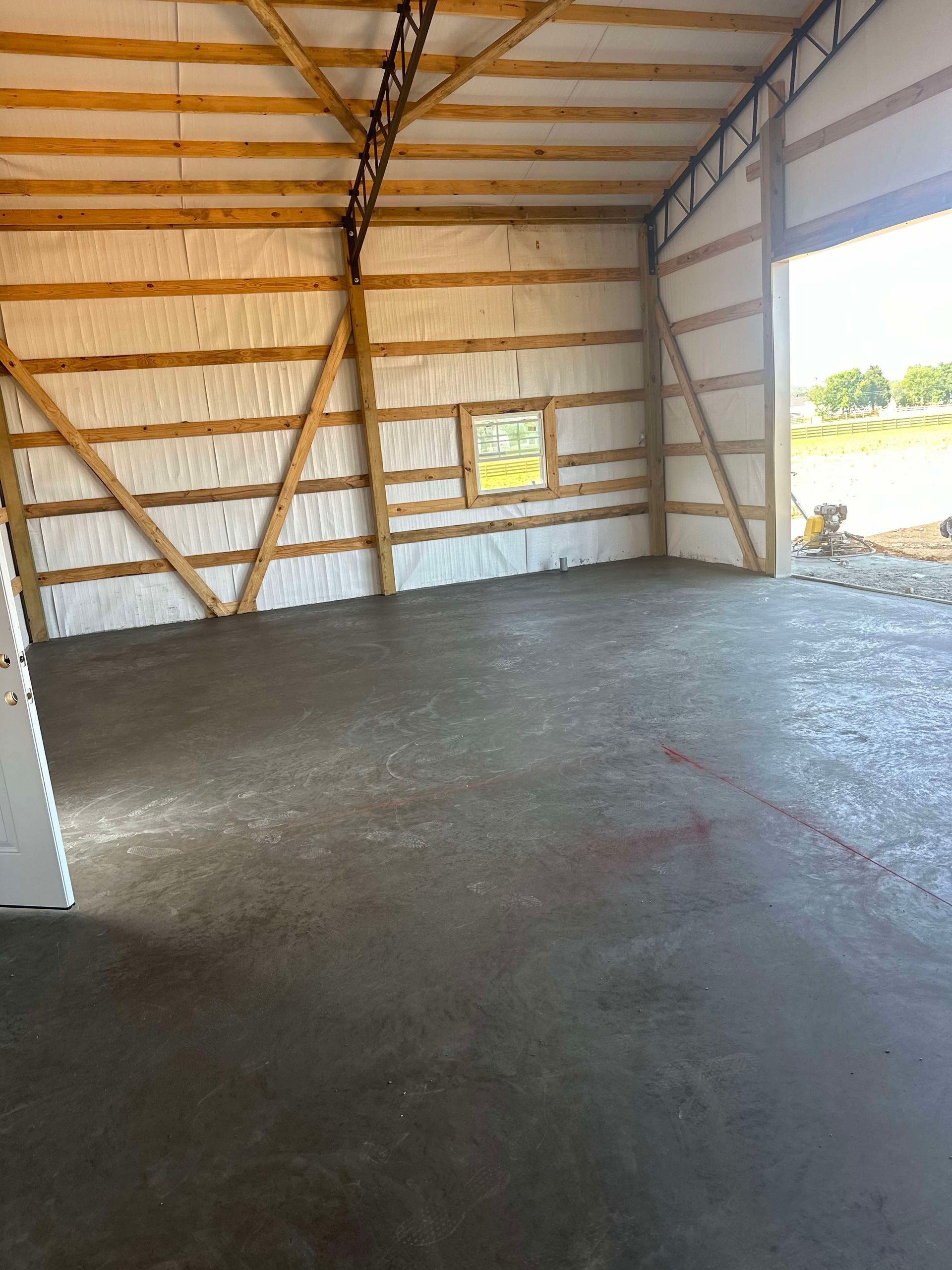 A large empty room with a concrete floor and wooden walls.