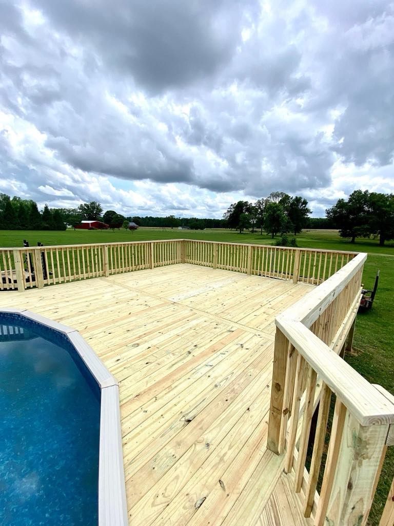 A large wooden deck next to a swimming pool.