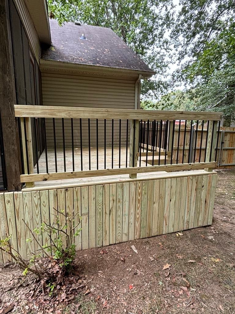 A wooden deck with a metal railing in front of a house.