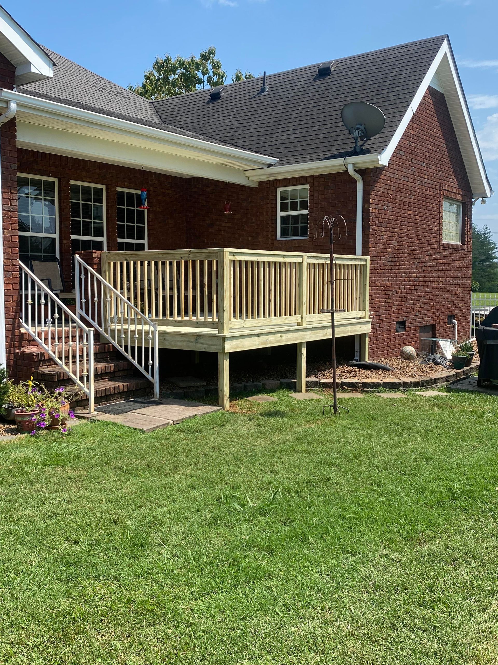 A brick house with a wooden deck and stairs in front of it.