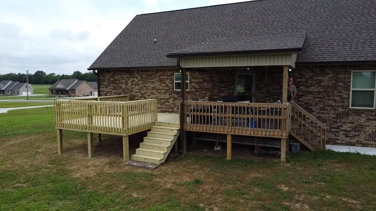 A wooden deck is sitting in front of a brick house.