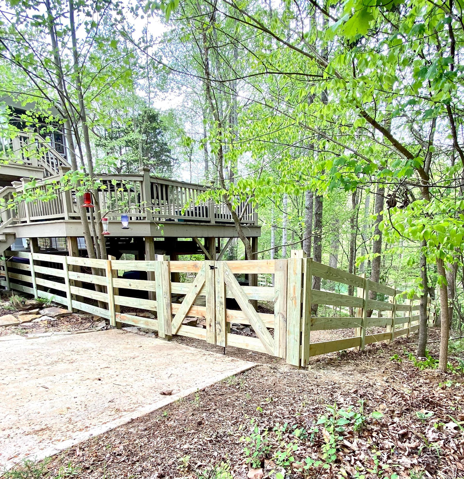 A wooden fence surrounds a wooden deck in the woods.