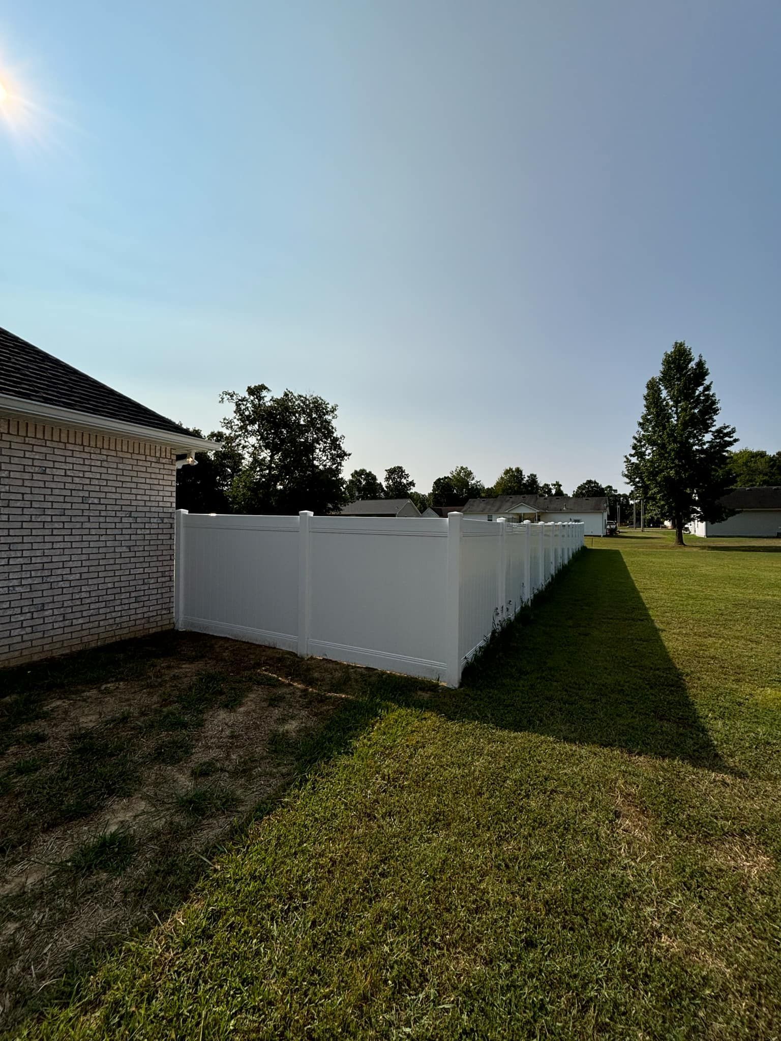 A white fence is sitting in the middle of a lush green field.