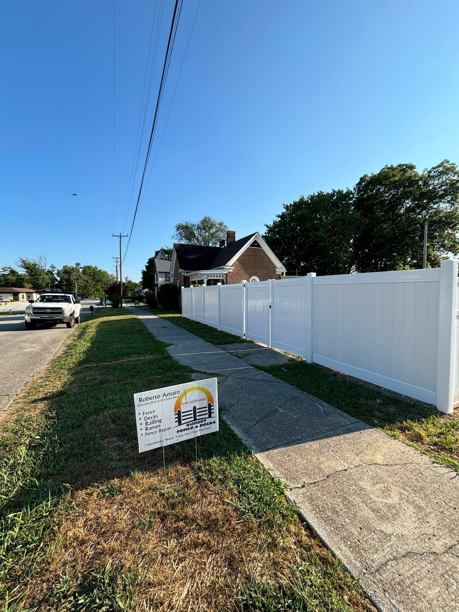 A white fence along a sidewalk next to a house.
