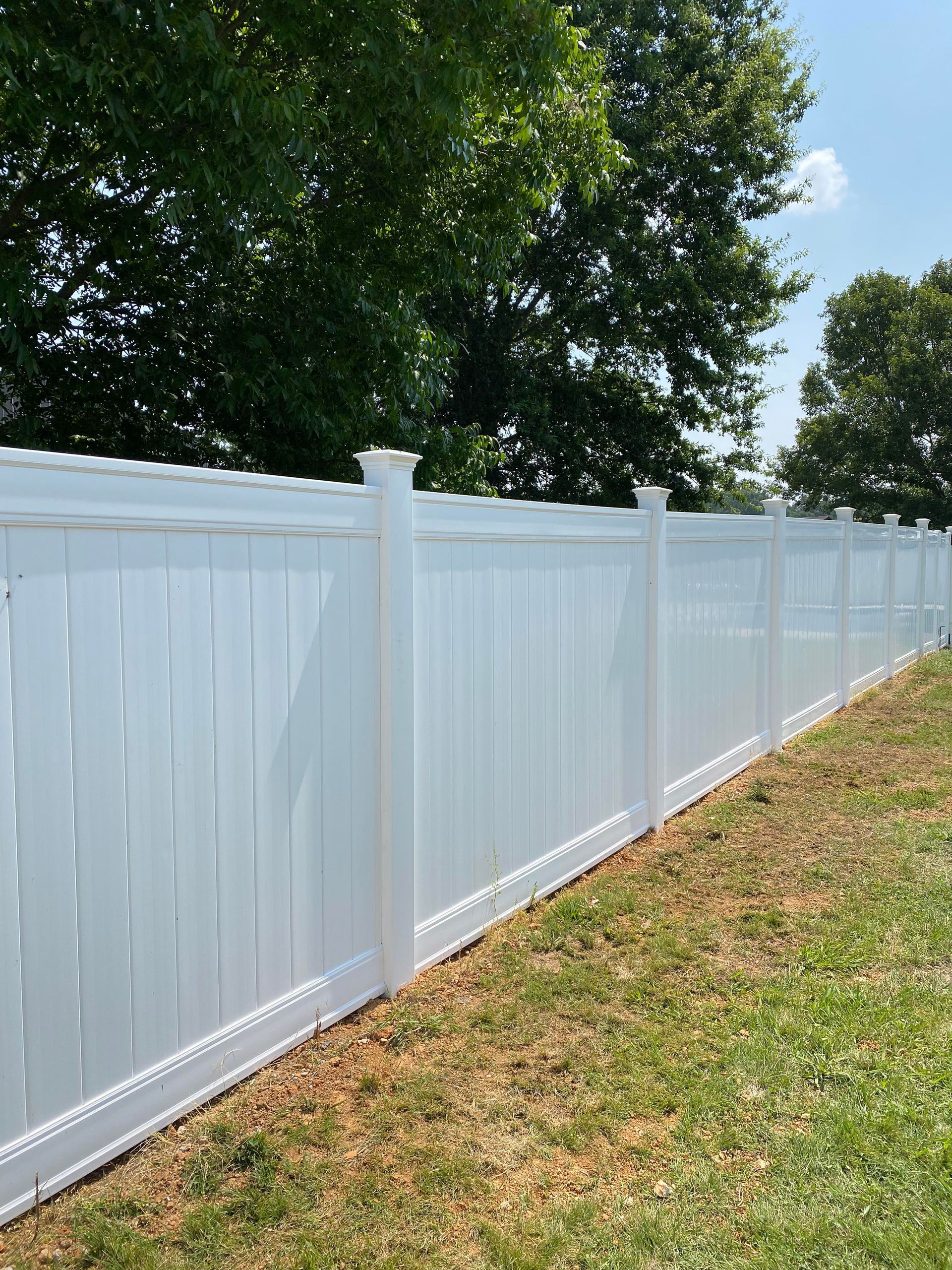 A white fence is sitting in the middle of a lush green field.