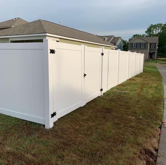 A white fence is sitting in the grass next to a house.
