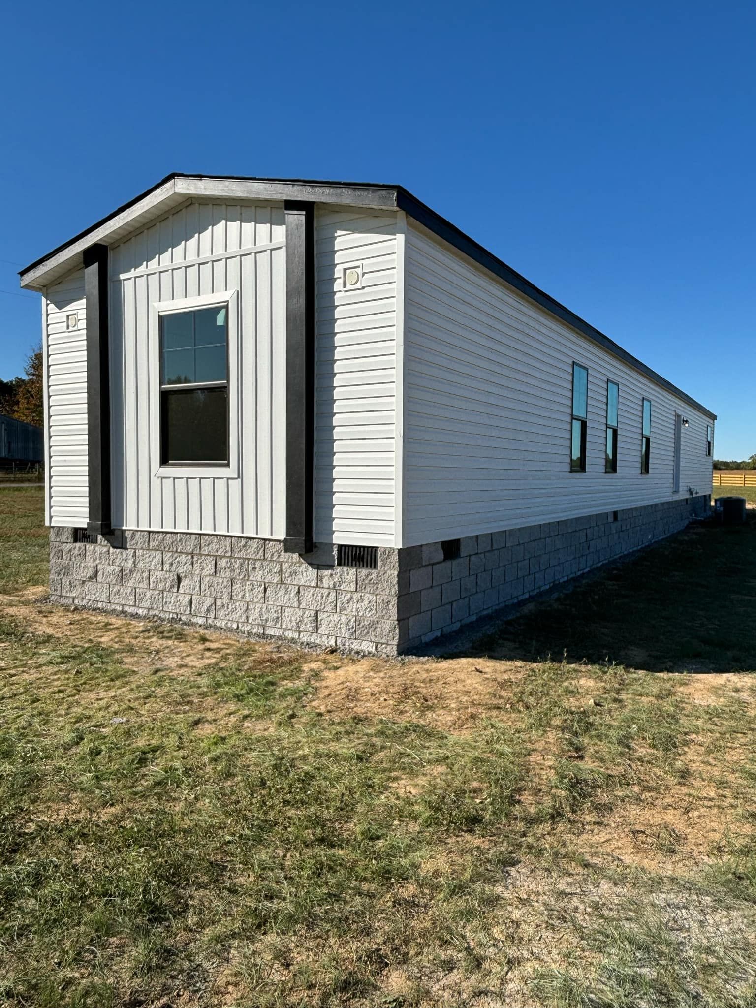 A mobile home is sitting in the middle of a grassy field.