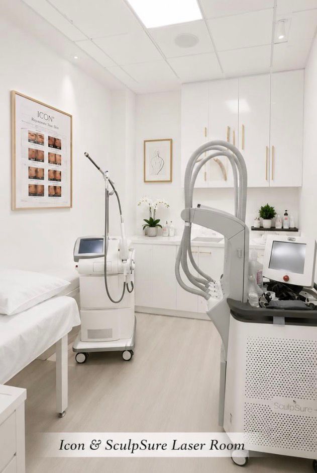 Bright white laser treatment room with spa bed, laser machine, and wall art.
