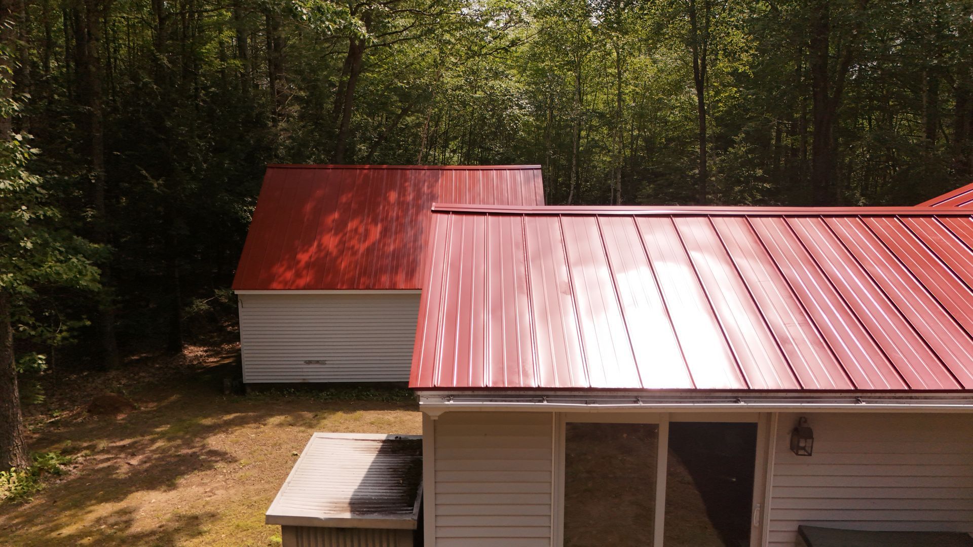 Red metal roofs on white buildings against a backdrop of trees.