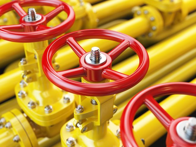 A close-up of three bright red industrial valves attached to vibrant yellow pipes.