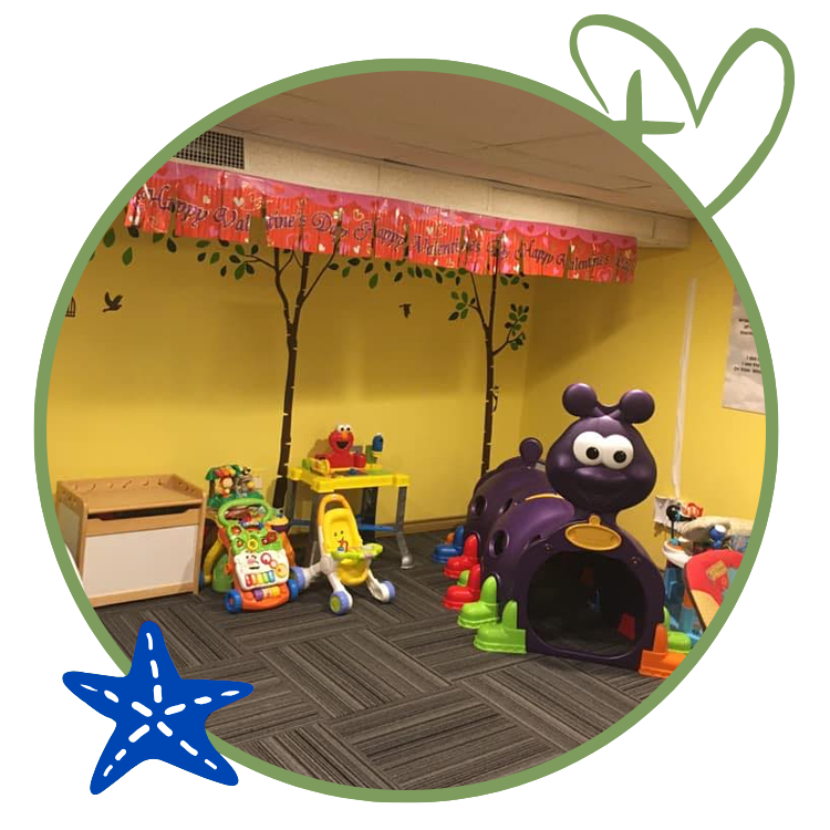 Playroom with toys, including a caterpillar tunnel and musical learning toys. Yellow walls, patterned floor.