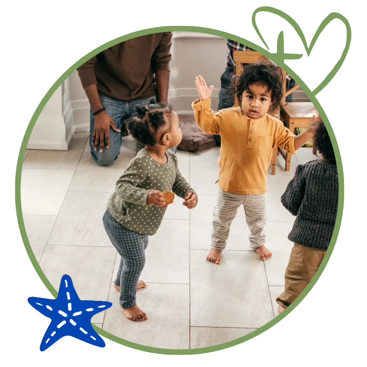 Children playing in a room, with an adult. One child has hands up. A starfish and leaf outline decorate the image.