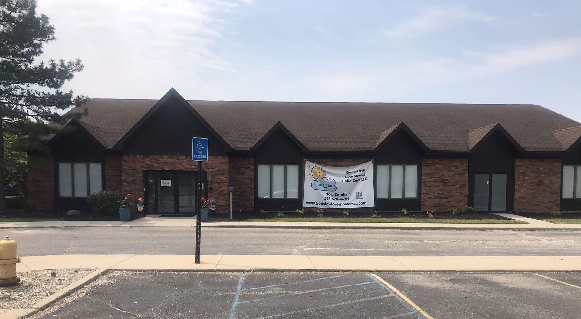 Building with brown roof, banner, accessible parking sign, and parking lot.