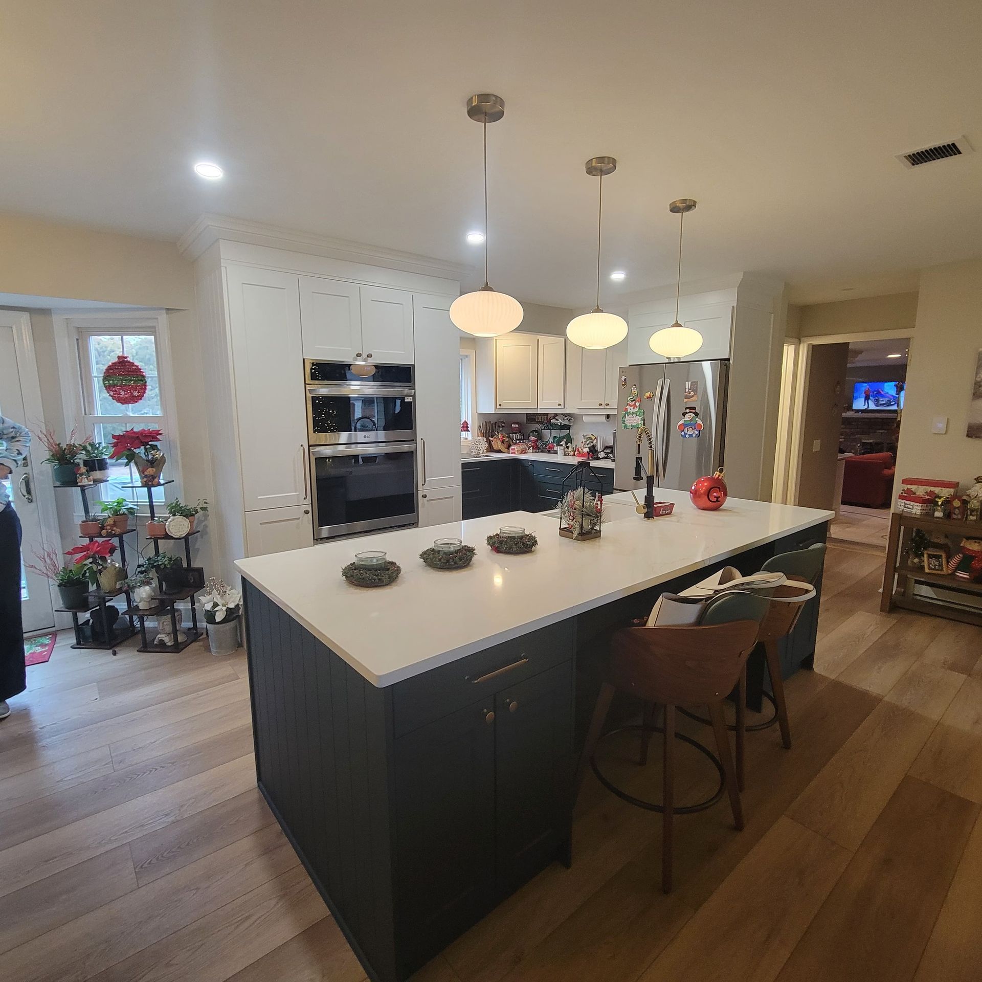 Modern kitchen with island, gray cabinets, white countertop, pendant lights, stainless steel appliances, and wood flooring.