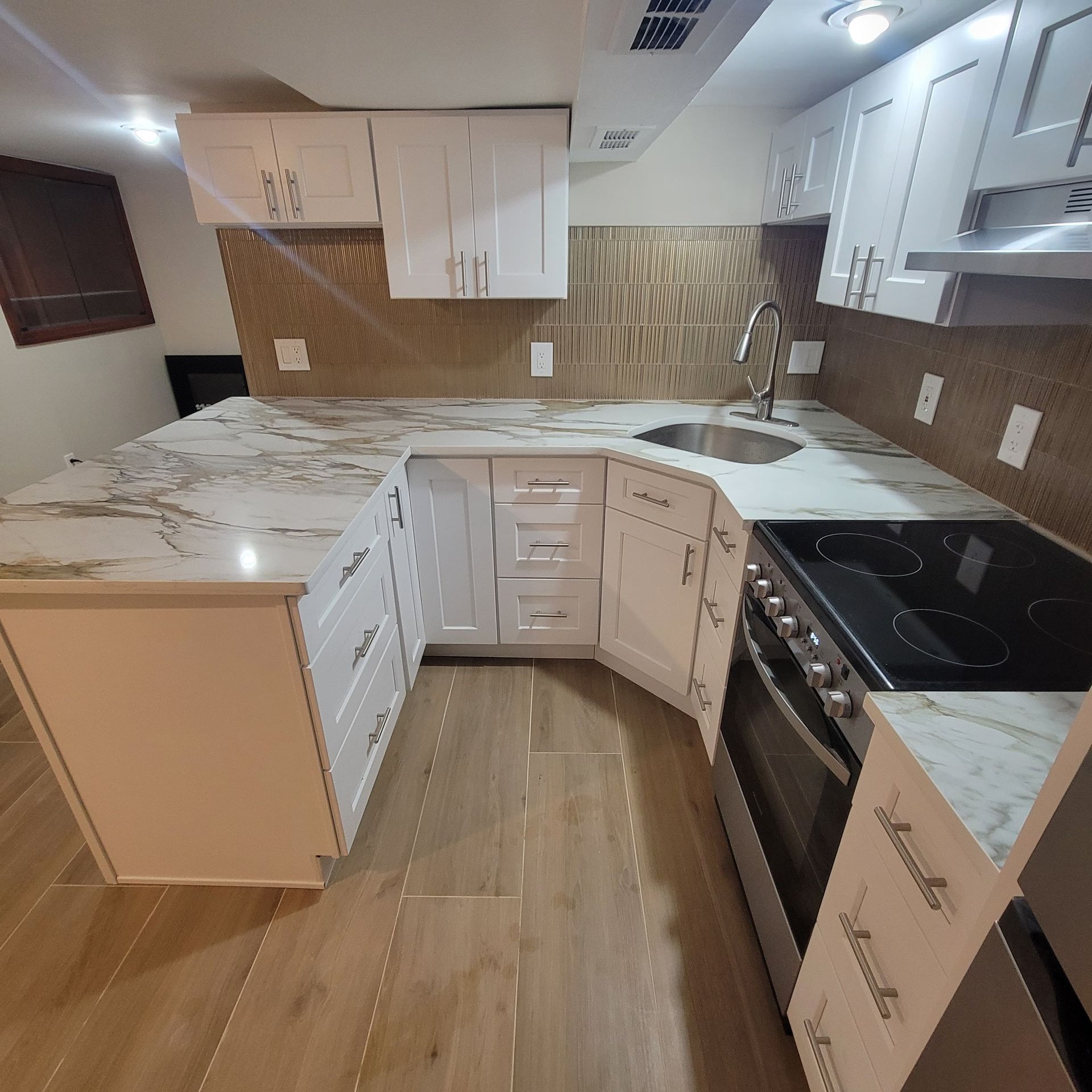 White kitchen with marble countertops, cabinets, and appliances.
