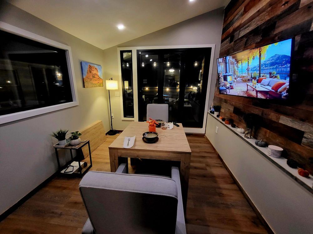 Cozy dining room with a wooden accent wall, a large window with a city view, and a table set for a meal.