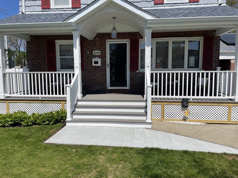 A brick house with a white porch and steps. A wheelchair ramp is to the right.