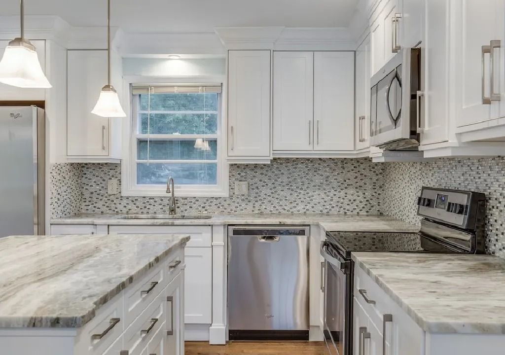 White kitchen with granite countertops, stainless steel appliances, and mosaic tile backsplash.