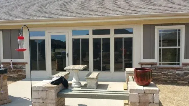 Back patio with white-framed windows, stone accents, and a bird feeder. Features outdoor furniture, with a brown flower pot.
