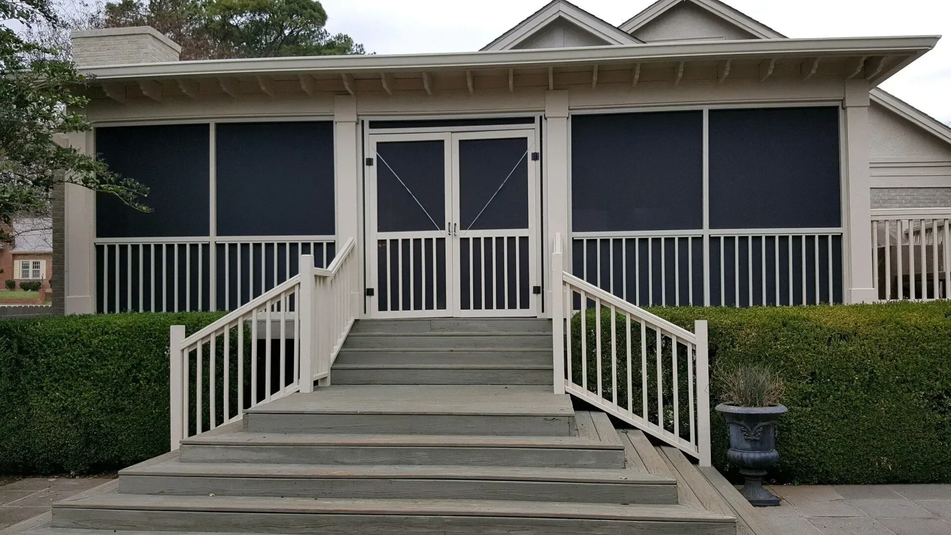 White screened porch with steps, railing, and closed doors.