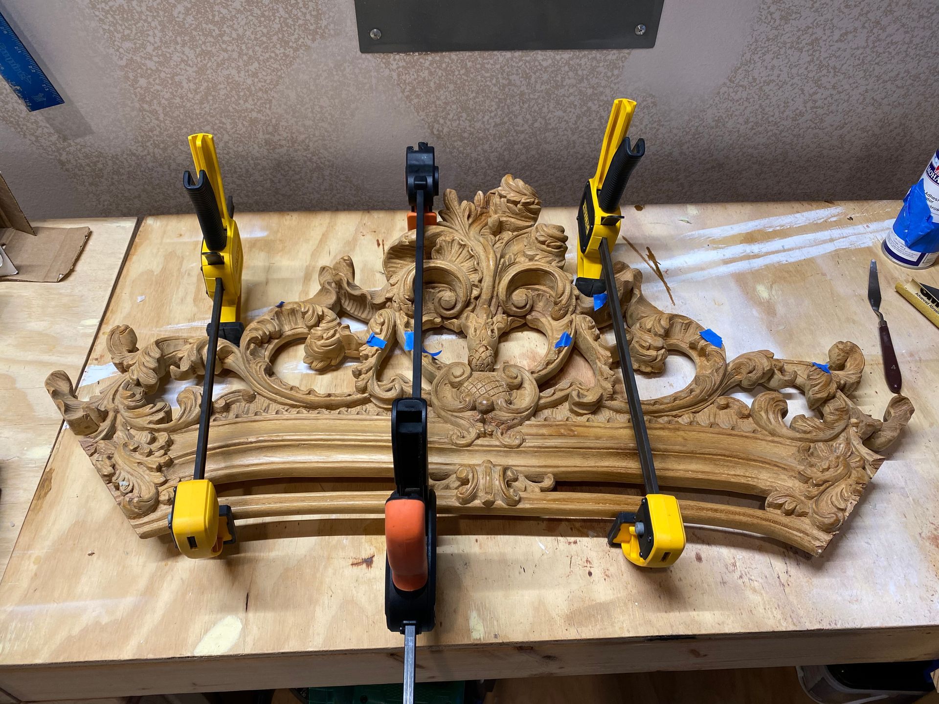 A piece of wood is being glued together with clamps on a wooden table.