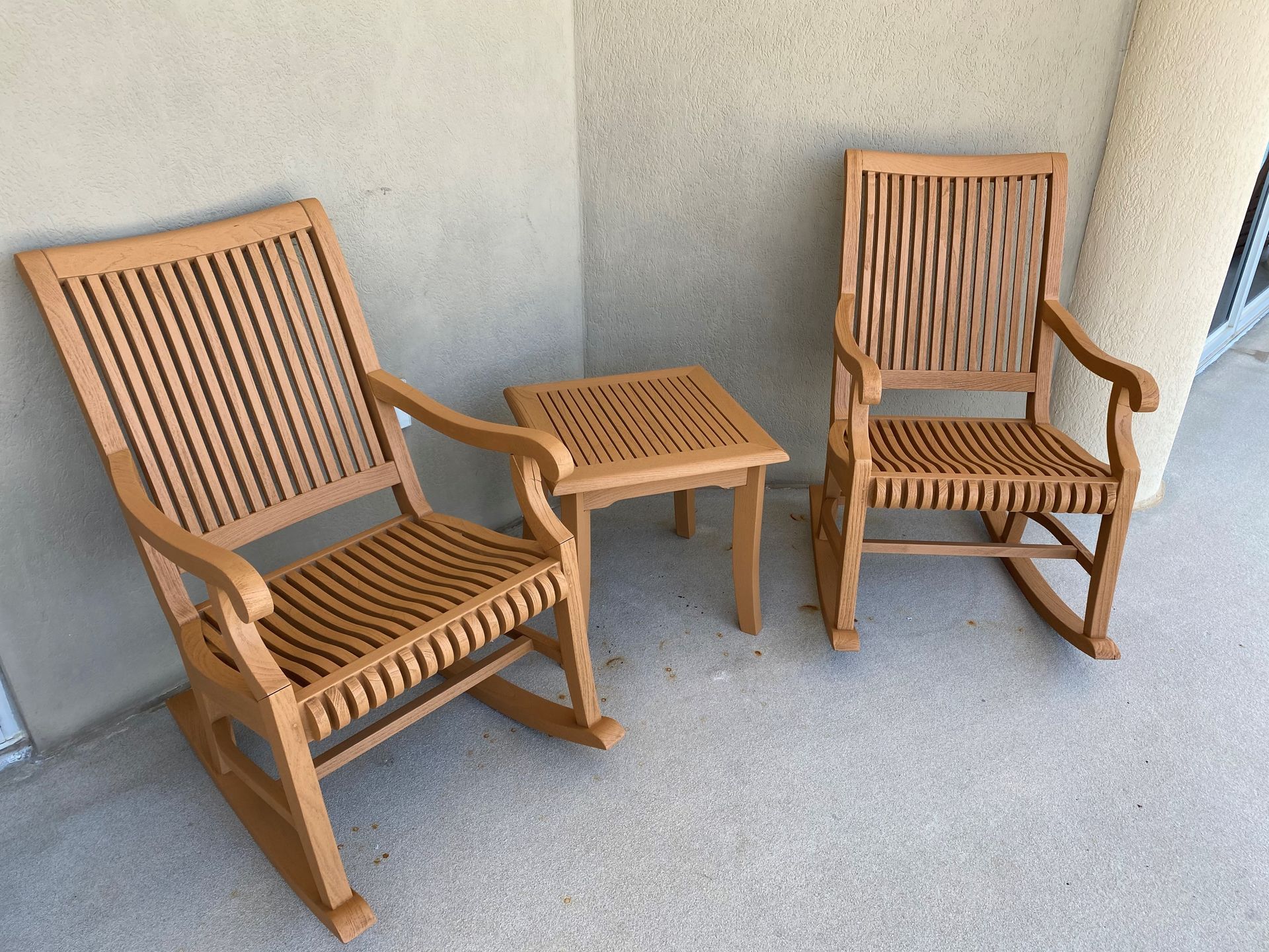 Two wooden rocking chairs and a small table on a porch