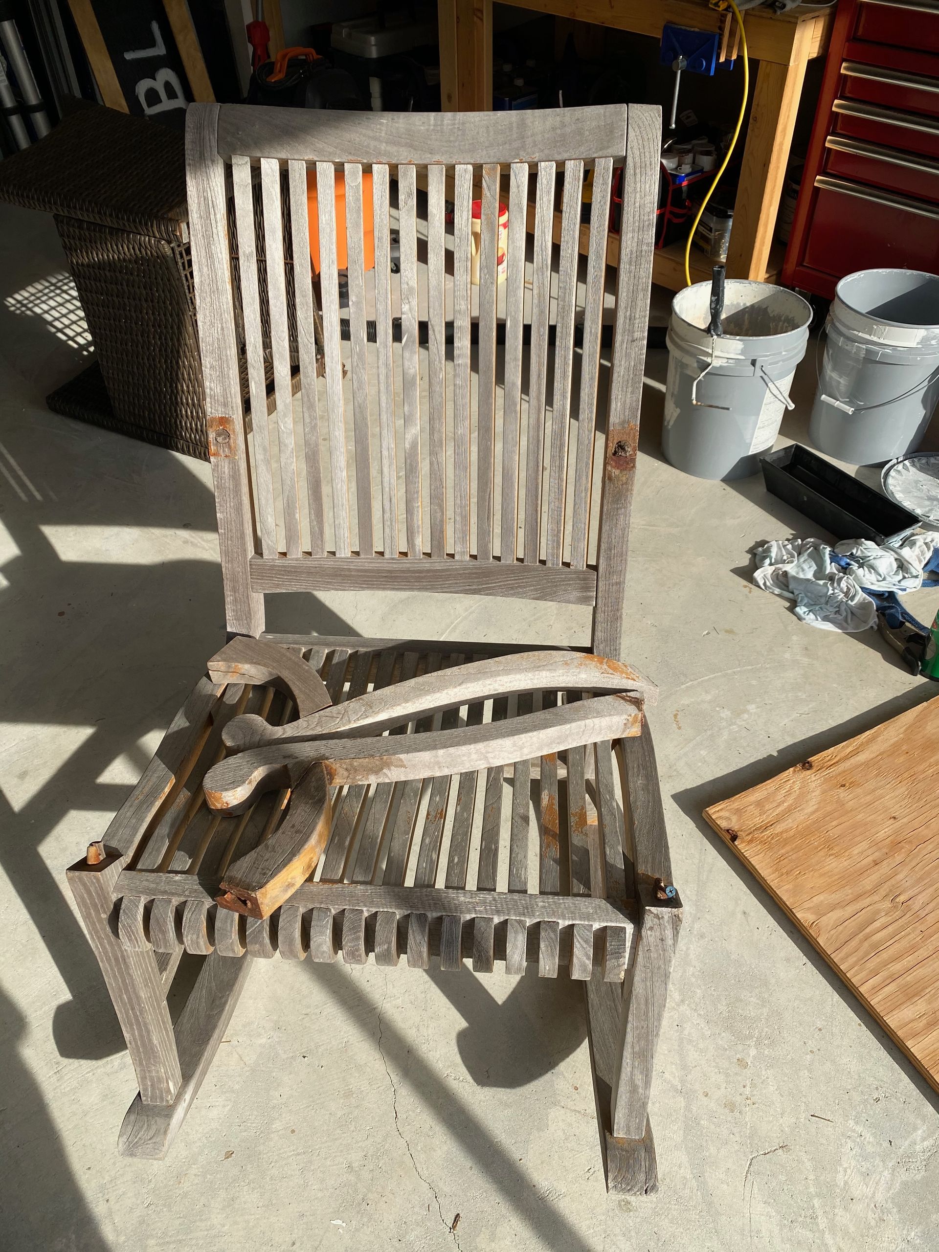 A wooden rocking chair with a broken arm rest