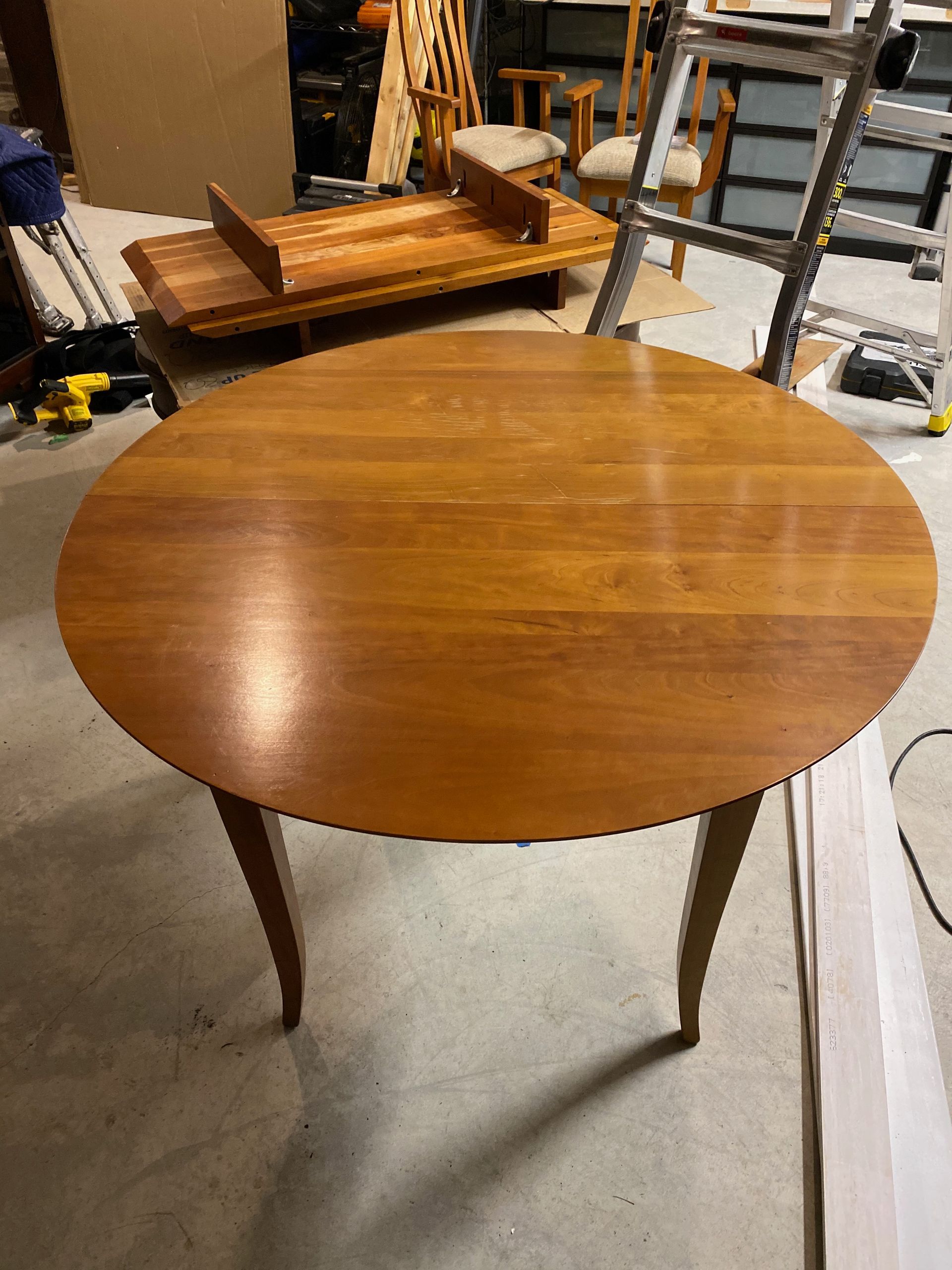 A round wooden table is sitting on a concrete floor in a room.
