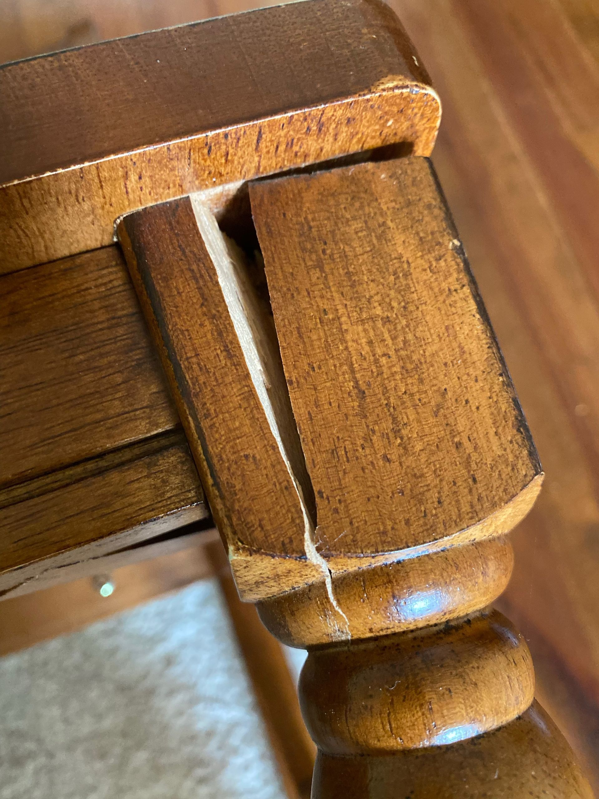A close-up of a wooden table with a broken leg
