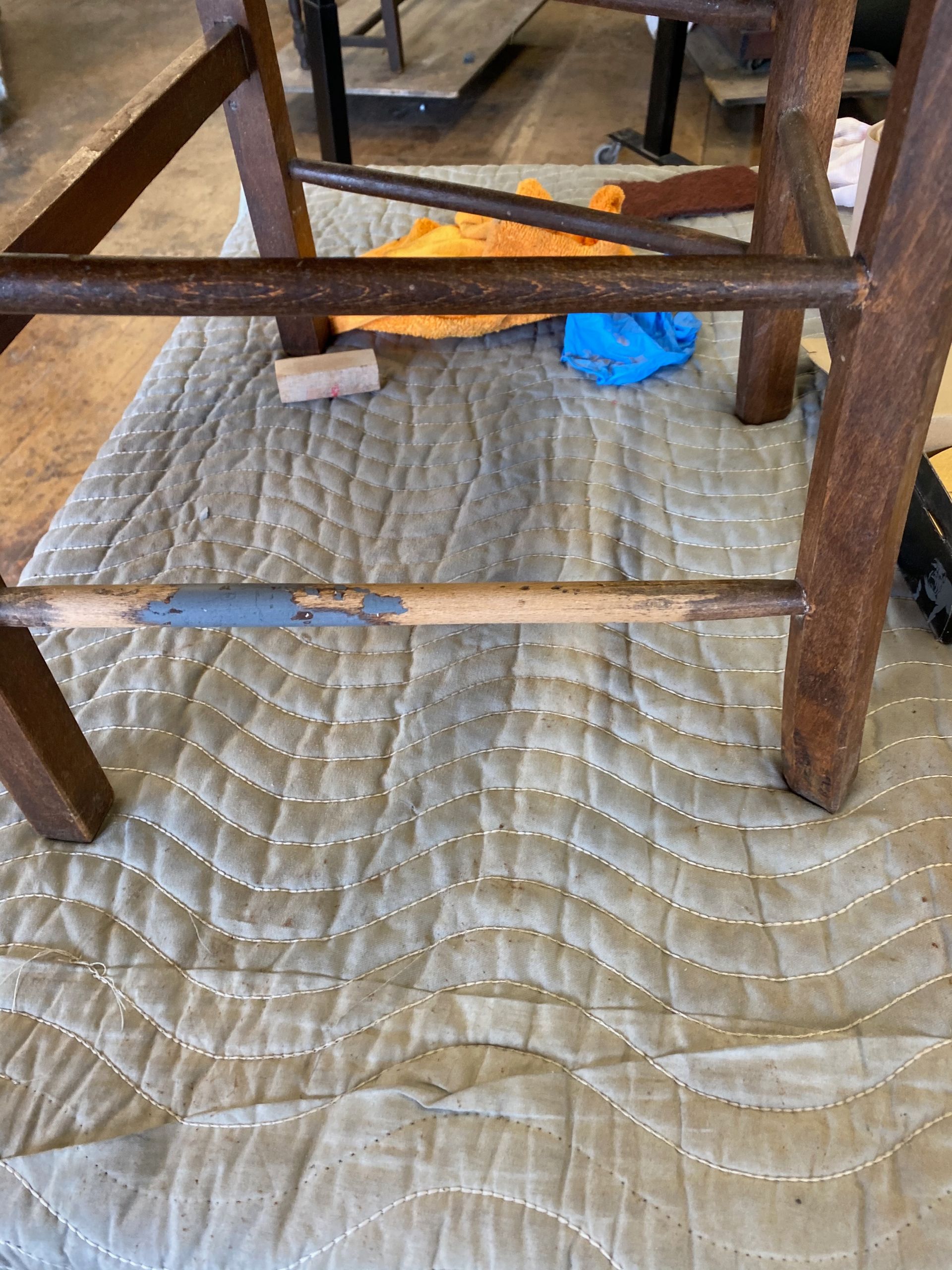 A wooden piece of furniture is sitting on a quilt on the floor.