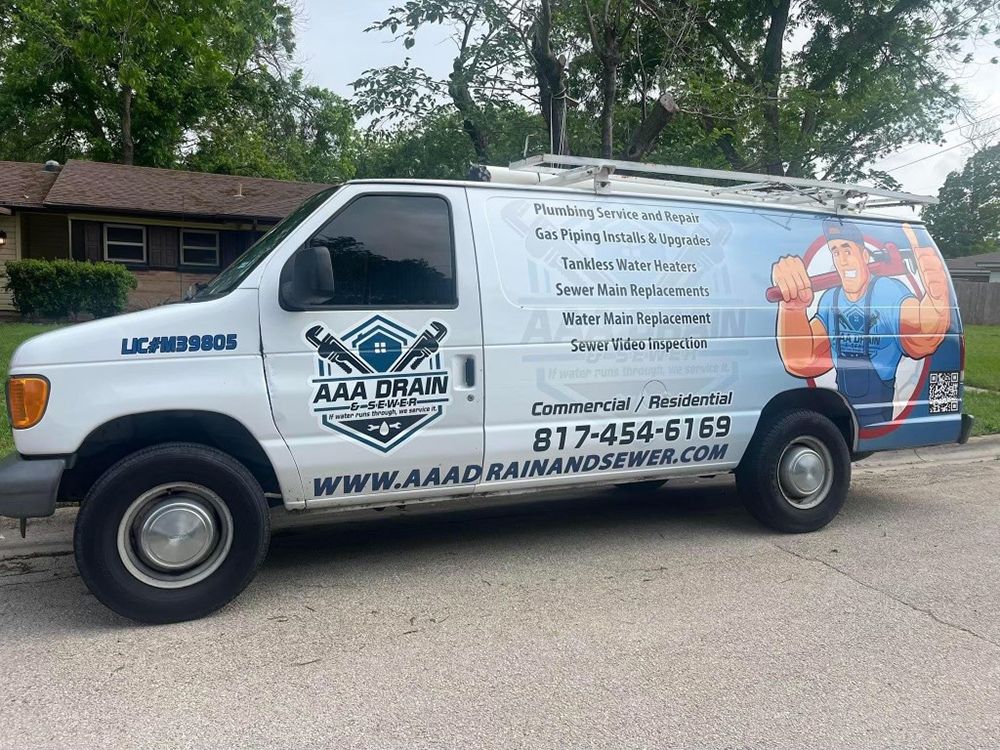 A white van with a plumber on the side is parked in front of a house.