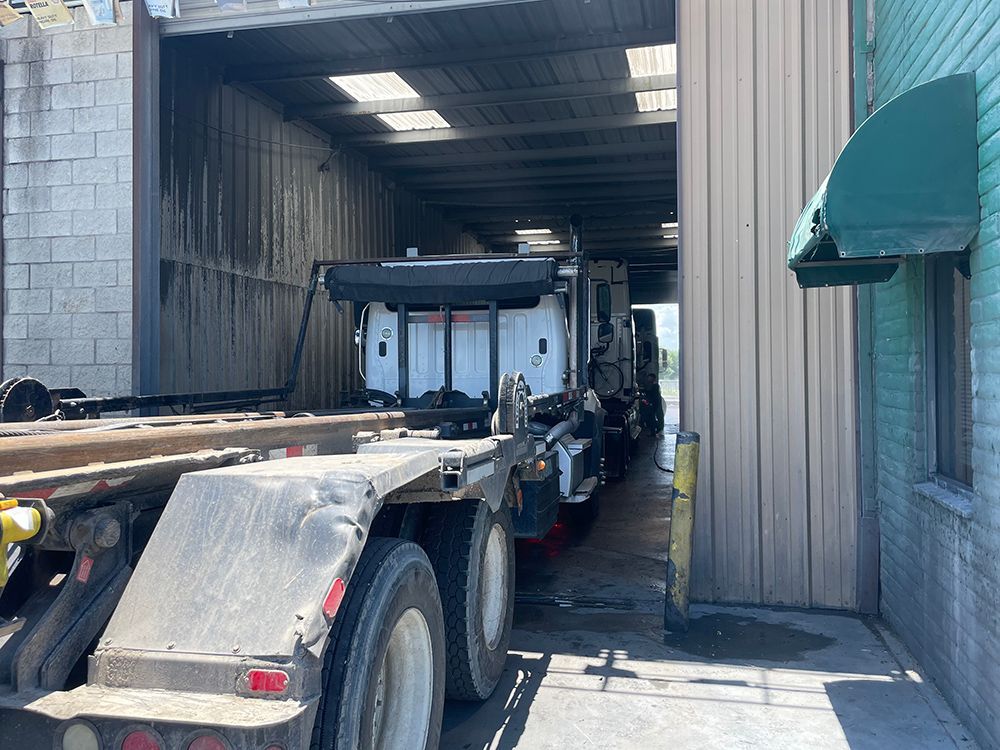 A dump truck is parked in a garage next to a building.