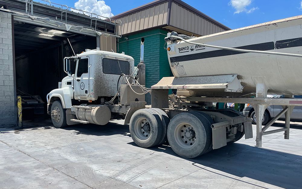 A truck with a trailer attached to it is parked in front of a building.