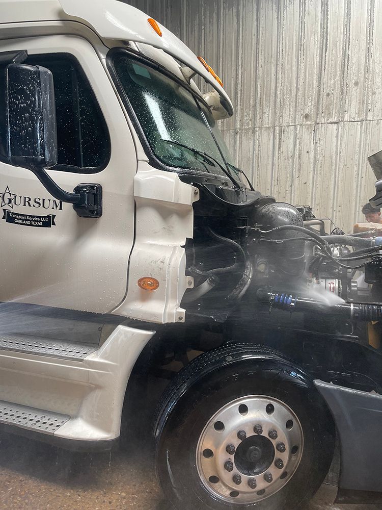 A white semi truck is being worked on in a garage.