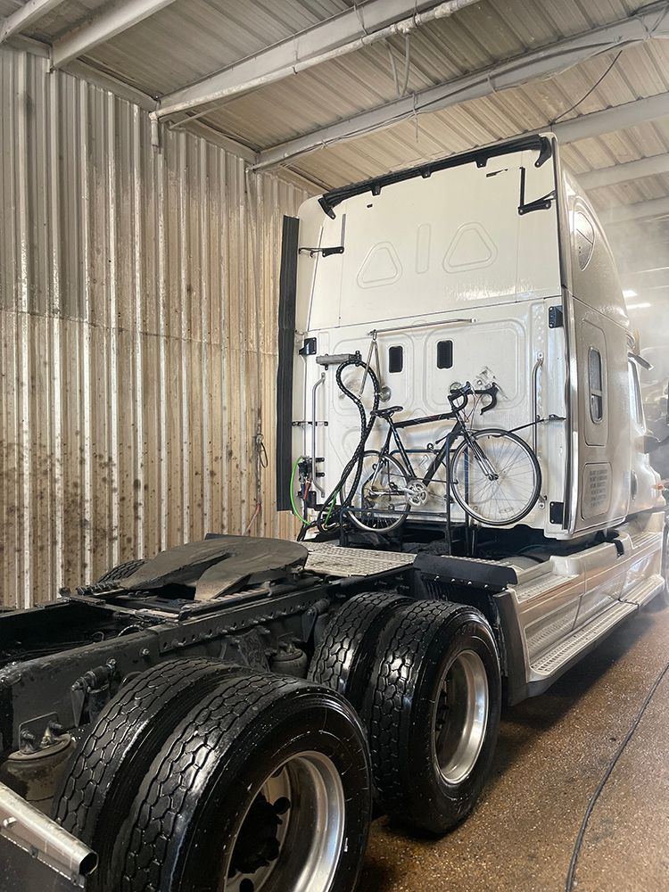 A semi truck with a bicycle attached to the back of it.