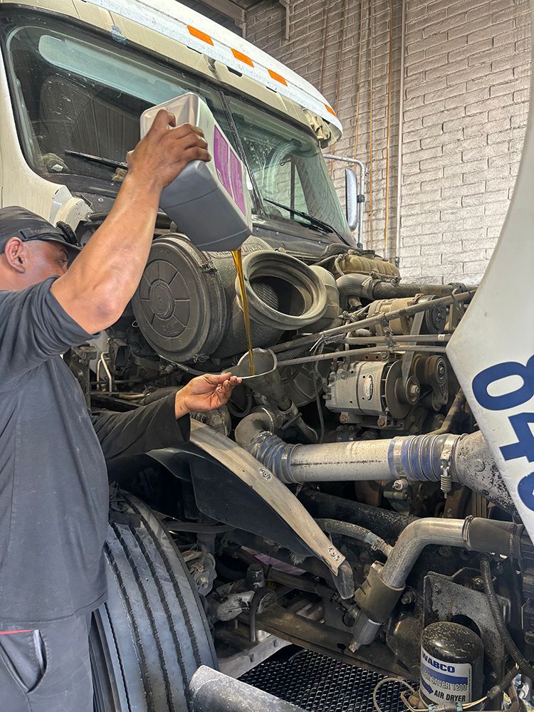 A man is working on the engine of a truck in a garage.