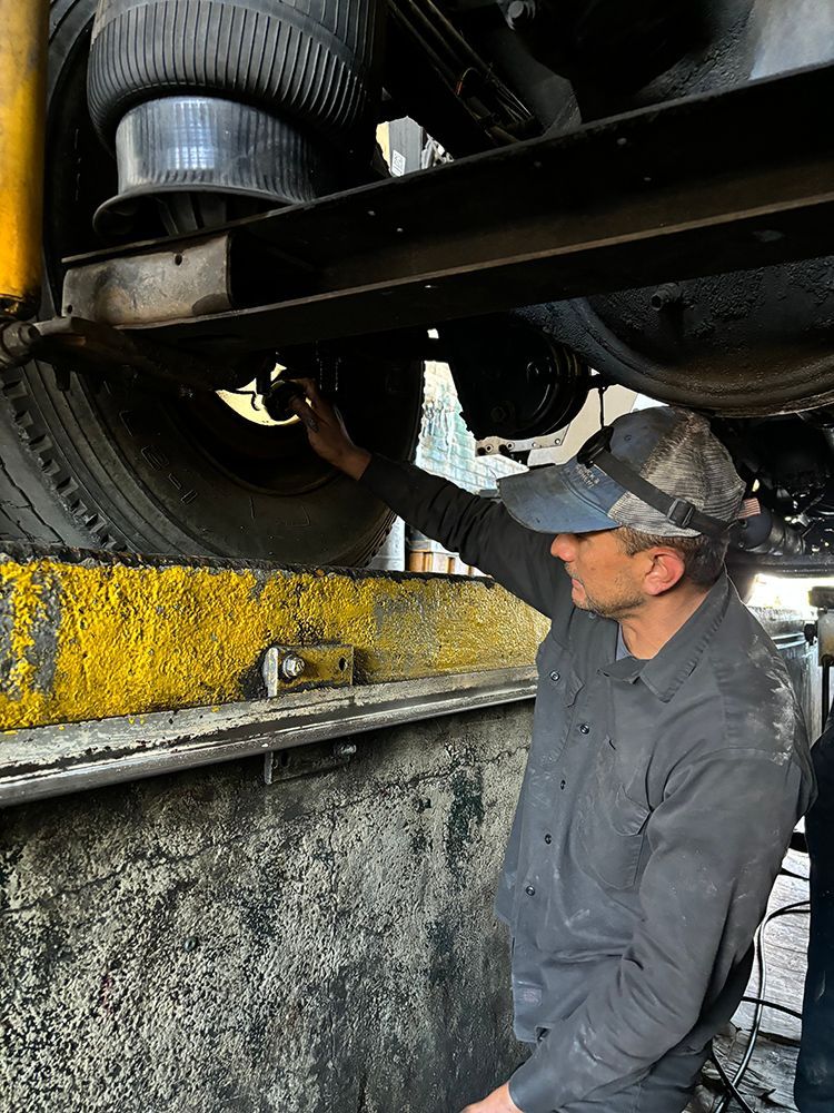 A man is working on the underside of a vehicle