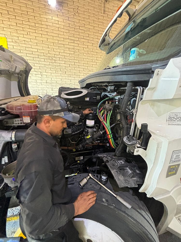 A man is working on the engine of a truck in a garage.